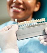 Dentist helping smiling patient select shade of veneer
