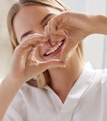 Woman holding hands up in heart shape to frame her smile