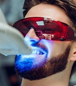 Man in protective glasses undergoing in-office teeth whitening
