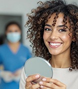 Patient smiling while holding small mirror