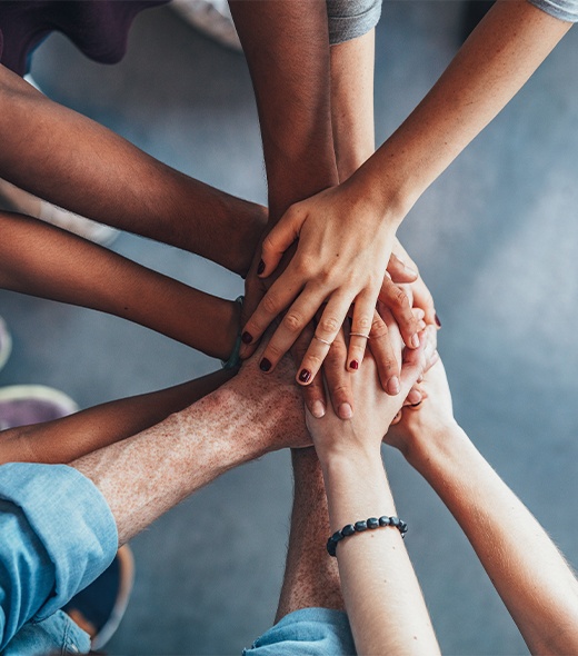 Group of people in circle with their hands in the center