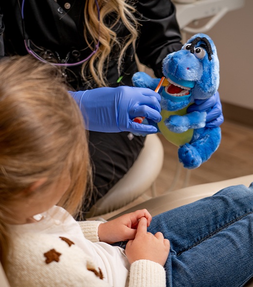 Dentist showing child tooth brushing technique after pulp therapy treatment