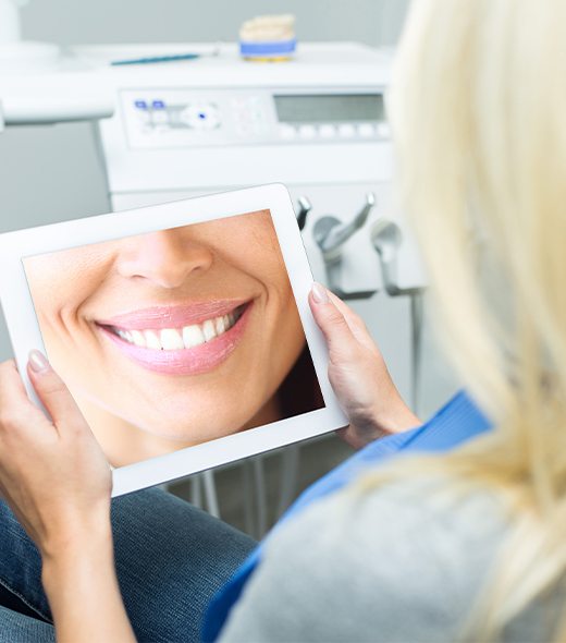 Woman looking at her transformed teeth in virtual smile design system