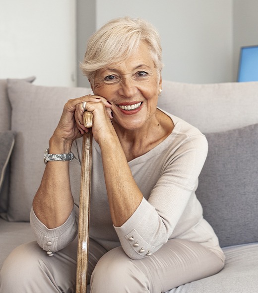 Older woman holding walking cane with dentures in Lubbock