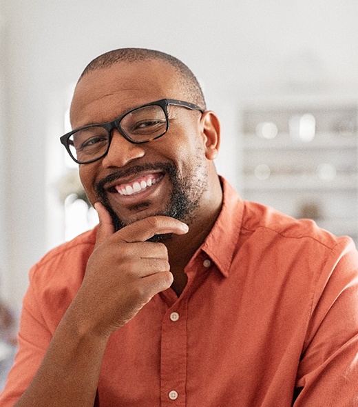 Man with dentures in Lubbock smiling in orange shirt