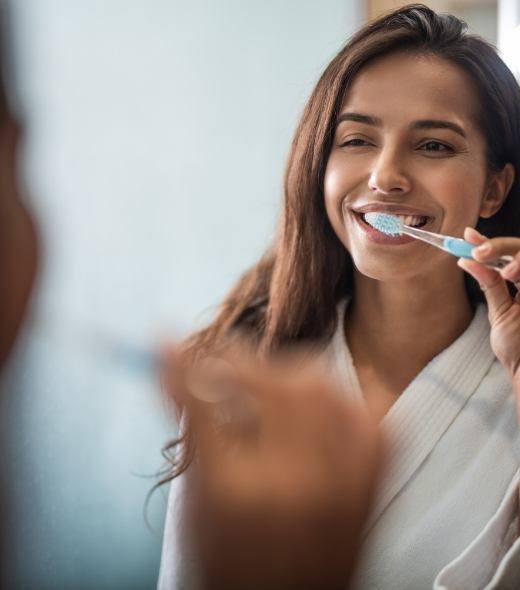 Woman brushing teeth to prevent dental emergencies in Lubbock 