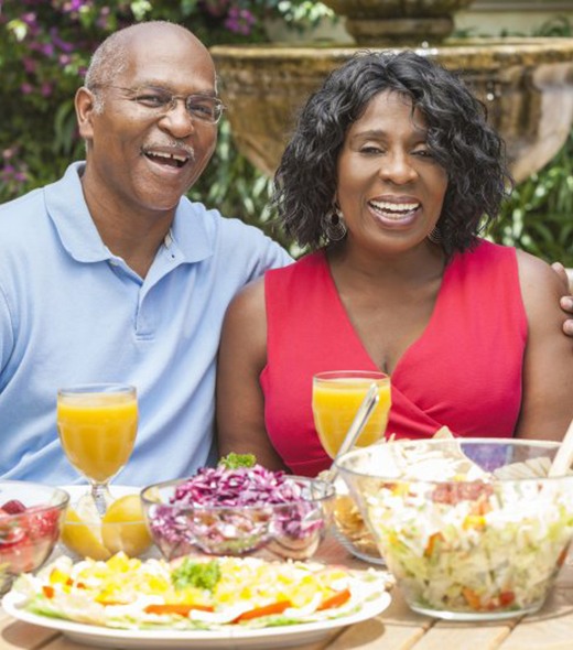 man and woman sitting at table with lots of food 