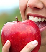person biting into a red apple 