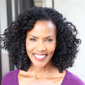 Woman in purple shirt with curly hair smiling