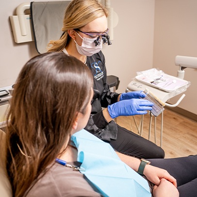 Dental team member and patient looking at tooth color chart