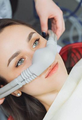 Hands placing nitrous oxide mask over woman’s nose