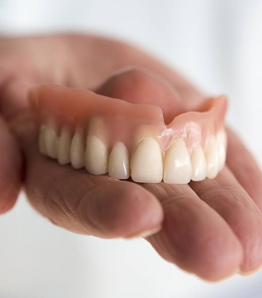 Hand holding full denture