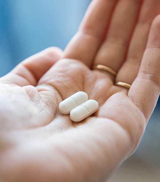 Patient holding antibiotic therapy pills for gum disease treatment