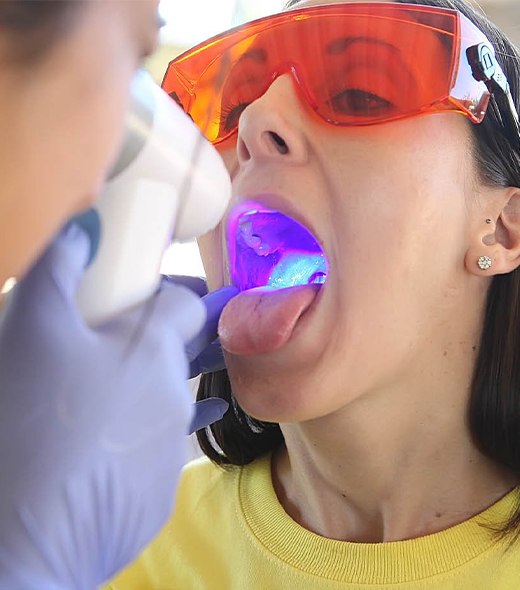 Dentist performing oral cancer screening using special light technology