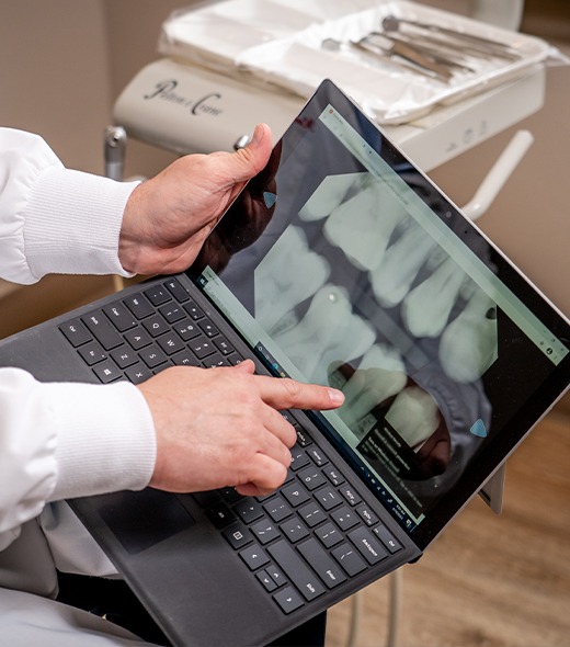 Dentist pointing to digital dental x-rays on computer screen