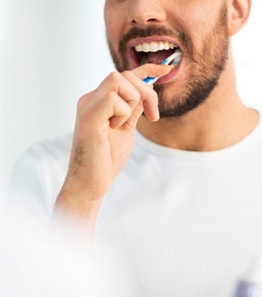 Closeup of man in white shirt brushing his teeth