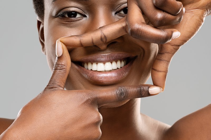 Smiling woman framing her teeth with her fingers