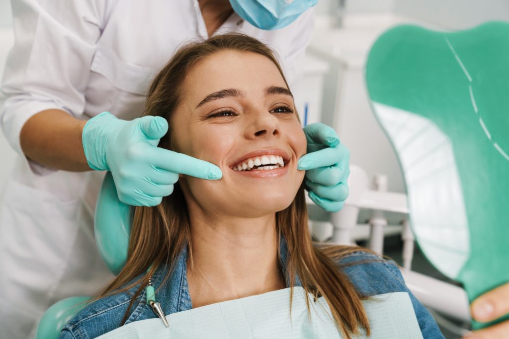 Woman with beautiful teeth smiling at reflection