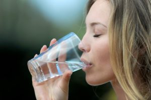 woman drinking water from a clear glass